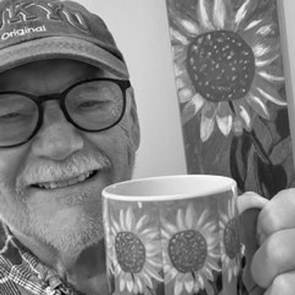 Smiling man holding a sunflower-patterned mug.
