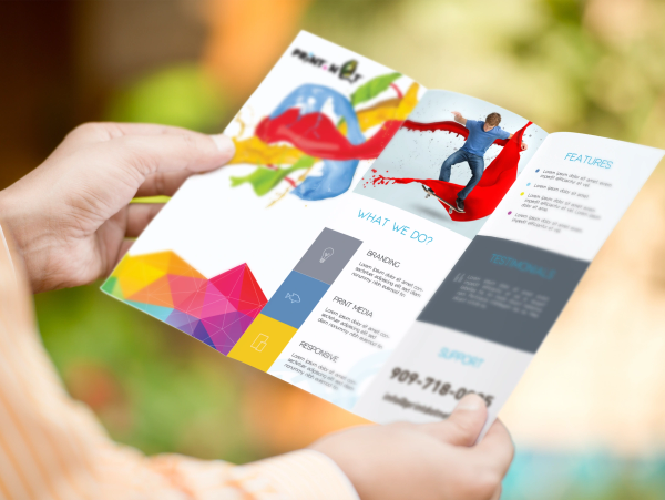 Person holding a colorful brochure with creative design and text.