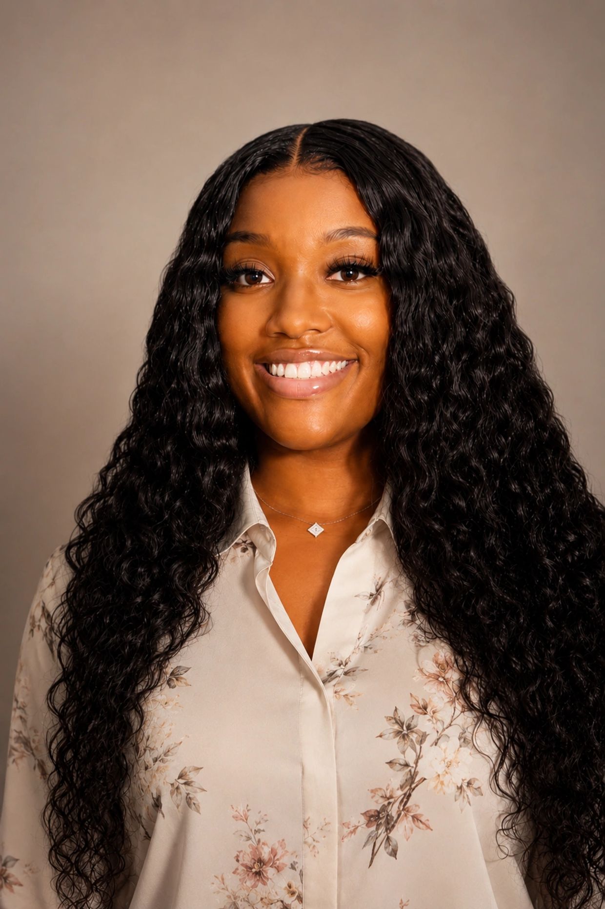 Smiling woman with long curly hair and floral blouse.