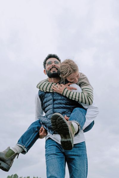 Man giving piggyback ride to a smiling child outdoors.