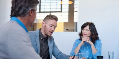 Two men and one woman are discussing writing and marketing strategies