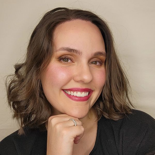 A smiling woman with shoulder-length brown hair and bright lipstick.
