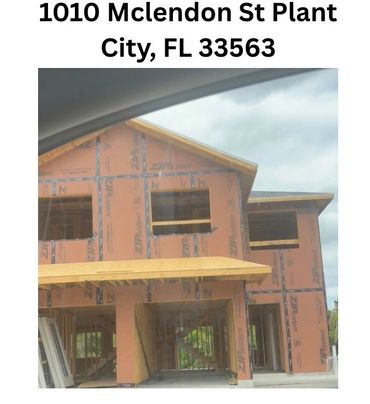 Two-story house under construction with exposed framing and sheathing.