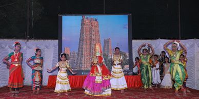 Group of children performing traditional Indian dance on stage.