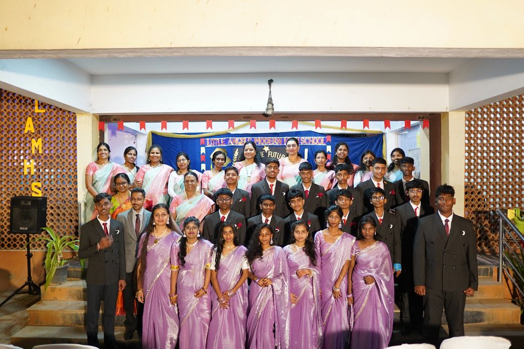 Group photo of students in formal attire and teachers in sarees at a school event.