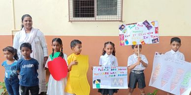 Children and a teacher holding colorful educational posters during a school activity.