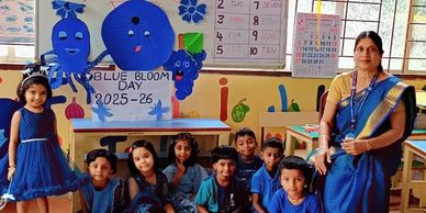 Children and a teacher dressed in blue celebrating Blue Bloom Day 2025-26 in a decorated classroom.