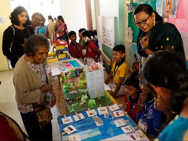 Children presenting a school project to adults in a classroom setting.