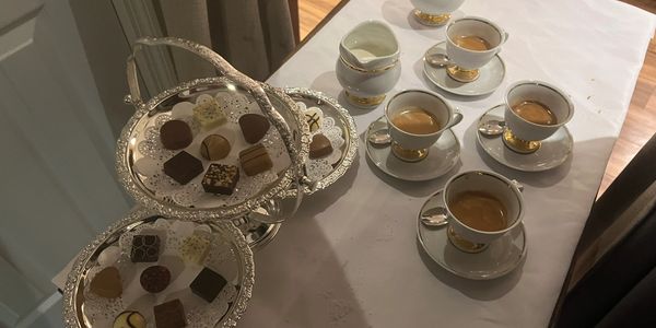 Elegant tea setup with espresso cups and assorted chocolates on a silver tray.