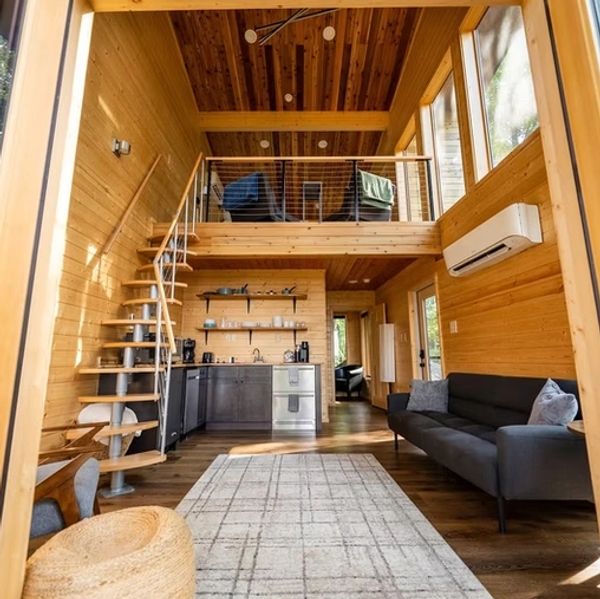 Cozy modern wooden cabin interior with loft and spiral staircase.