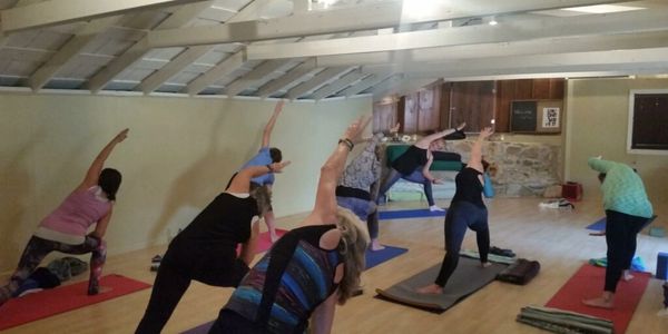 Group yoga class practicing side stretch poses in a bright studio.