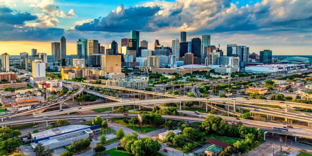 City skyline with highways and cloudy sky at sunset.