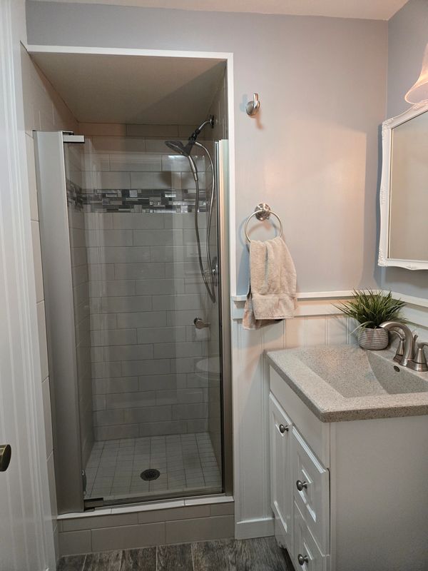 Modern bathroom with glass shower door and white vanity.