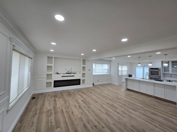 Modern open-concept living room and kitchen with wood flooring and recessed lighting.