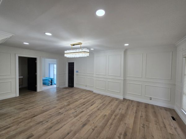 Empty room with wood flooring and white paneled walls under modern lighting.