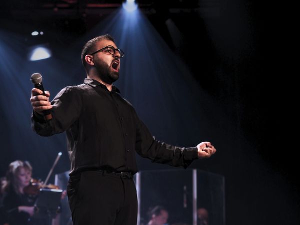 Un chanteur passionné sur scène, éclairé par un projecteur.