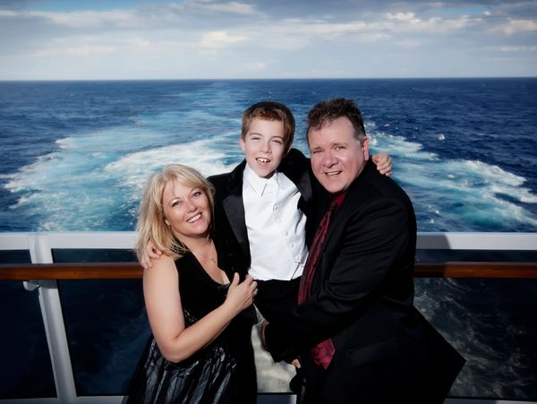 A happy family dressed formally on a cruise ship with the ocean in the background.
