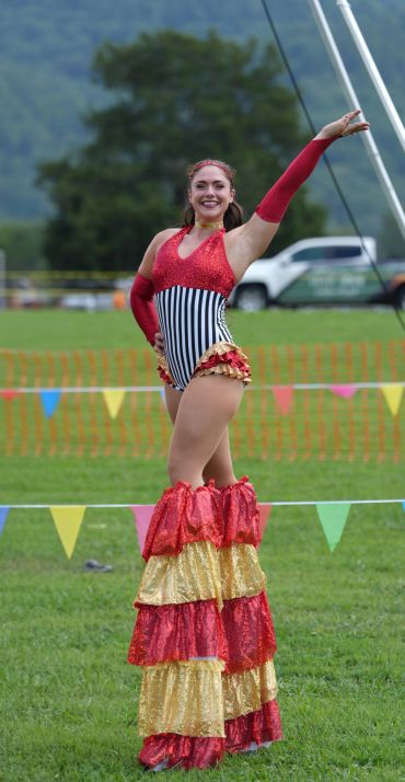 Performer in colorful costume on stilts at outdoor event.