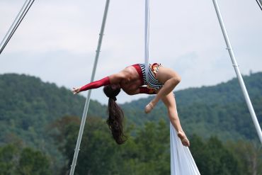 Aerial silk performer poses gracefully outdoors.