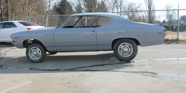 Classic gray muscle car with raised front suspension parked outdoors.
