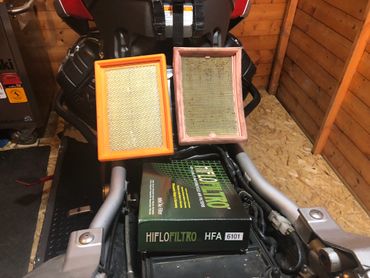 Old dirty motorcycle air filter change next to a new air filter