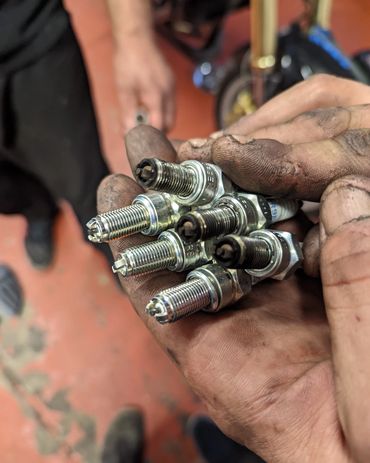 Old spark plugs being changed next to new spark plug comparison.