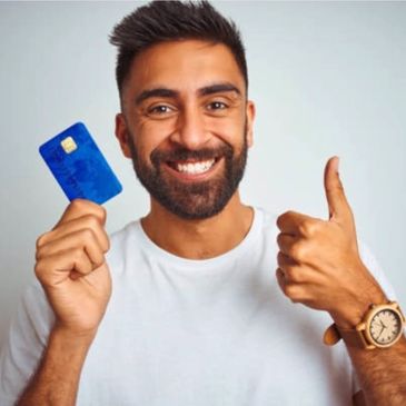 Smiling man holding a blue credit card and giving a thumbs up.