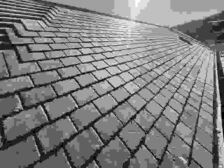 A roof covered with neatly arranged slate tiles under bright sunlight.