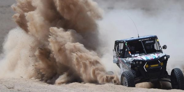 Off-road vehicle kicking up dust during a desert race.