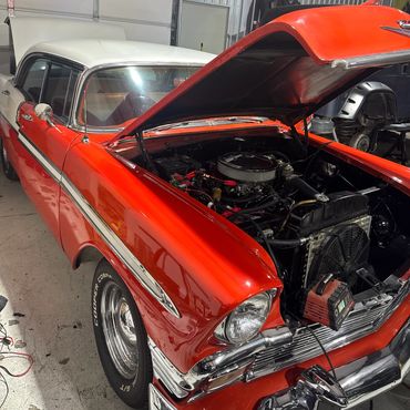 Classic red vintage car with hood open, showcasing its engine.