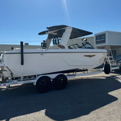 A white boat on a trailer parked outdoors under a clear blue sky.