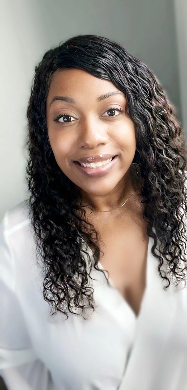 Smiling woman with curly hair in a white blouse.