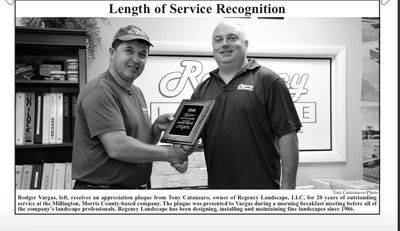 Two men shaking hands during a length of service recognition event.