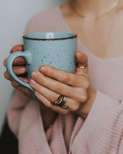 Person holding a speckled blue ceramic mug with both hands.