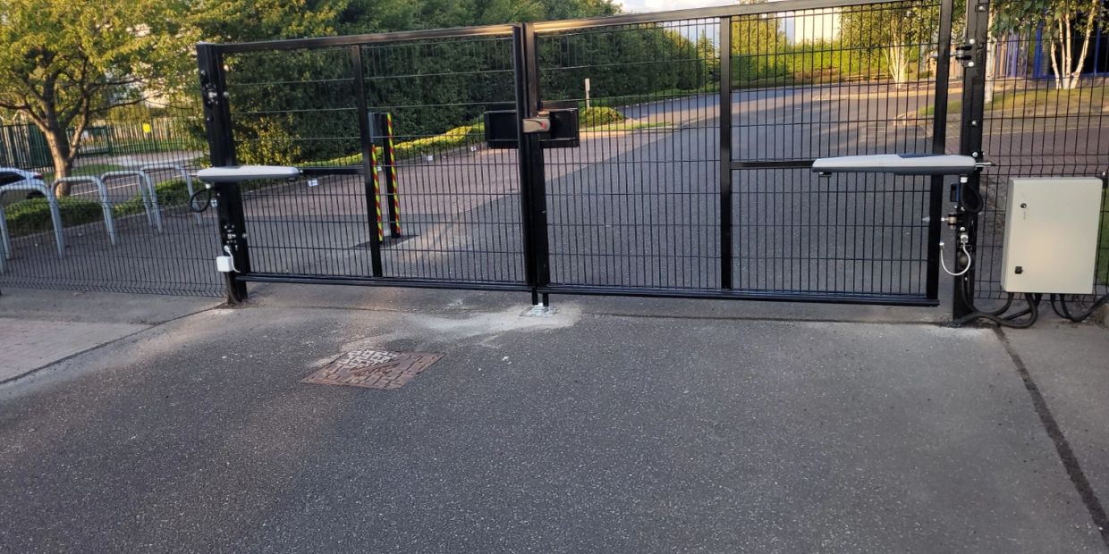 Automatic black metal gate blocking a road.