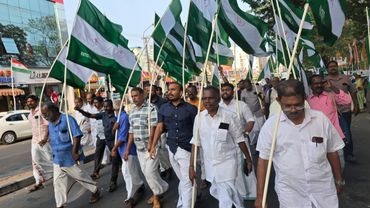 A group of men marching with green and white flags on a street.