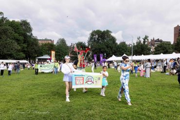 People holding a banner at an outdoor event.
