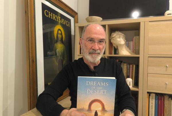 Man holding a book titled 'Dreams of the Desert'.