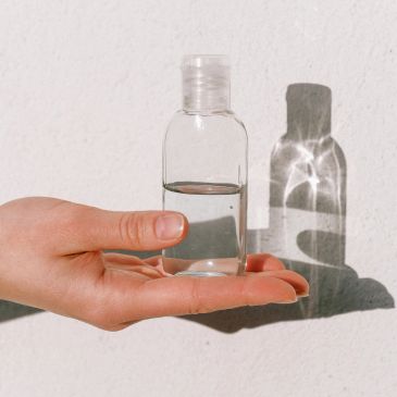 Mano sosteniendo una botella transparente con líquido.