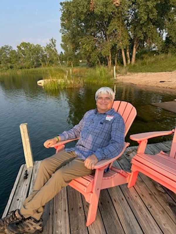 Man relaxing on pink chair by the lake.