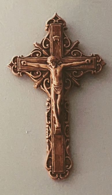 Ornate wooden crucifix with Jesus figure mounted on a plain wall.