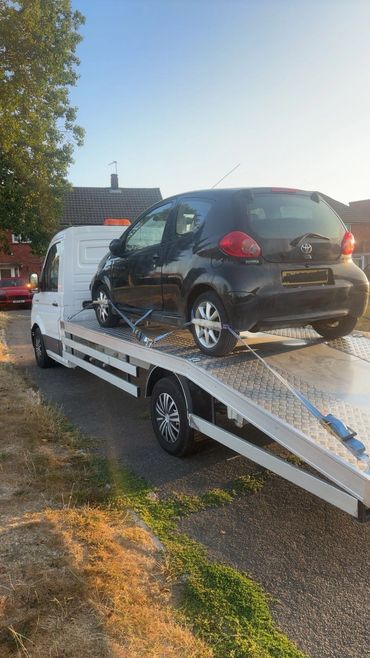 Black car being towed on a flatbed truck.