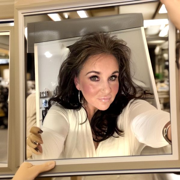Woman taking a selfie in a mirror with a confident expression.