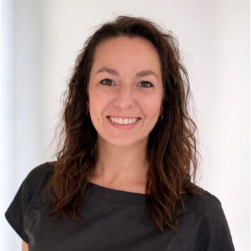 Smiling woman with curly hair against a white background.