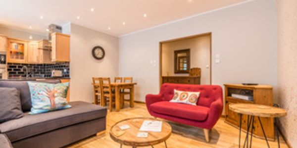 Cozy living room with vibrant red sofa and wooden dining set.
