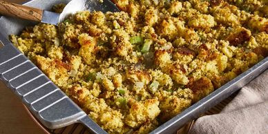 A pan of golden-brown cornbread stuffing with celery and herbs.