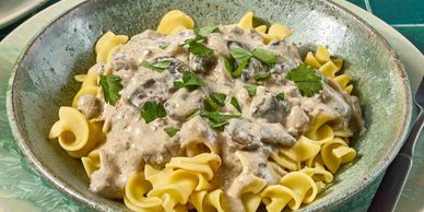 Creamy mushroom sauce over egg noodles garnished with parsley.