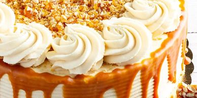 Close-up of a caramel-drizzled cake topped with whipped cream and crushed nuts.