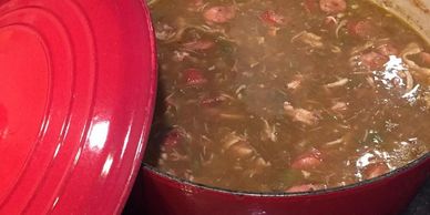 Red pot filled with simmering stew containing meat and vegetables.