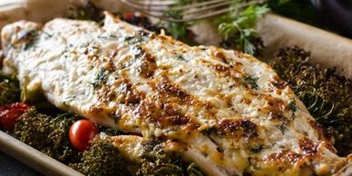A baked fish fillet with herbs and roasted vegetables.